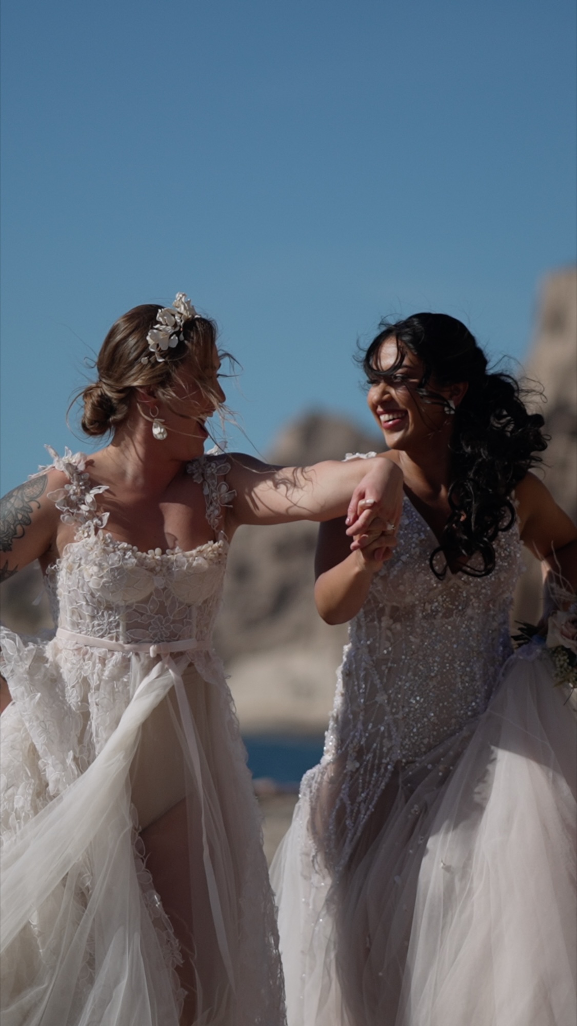 Two brides running on beach in Santorini