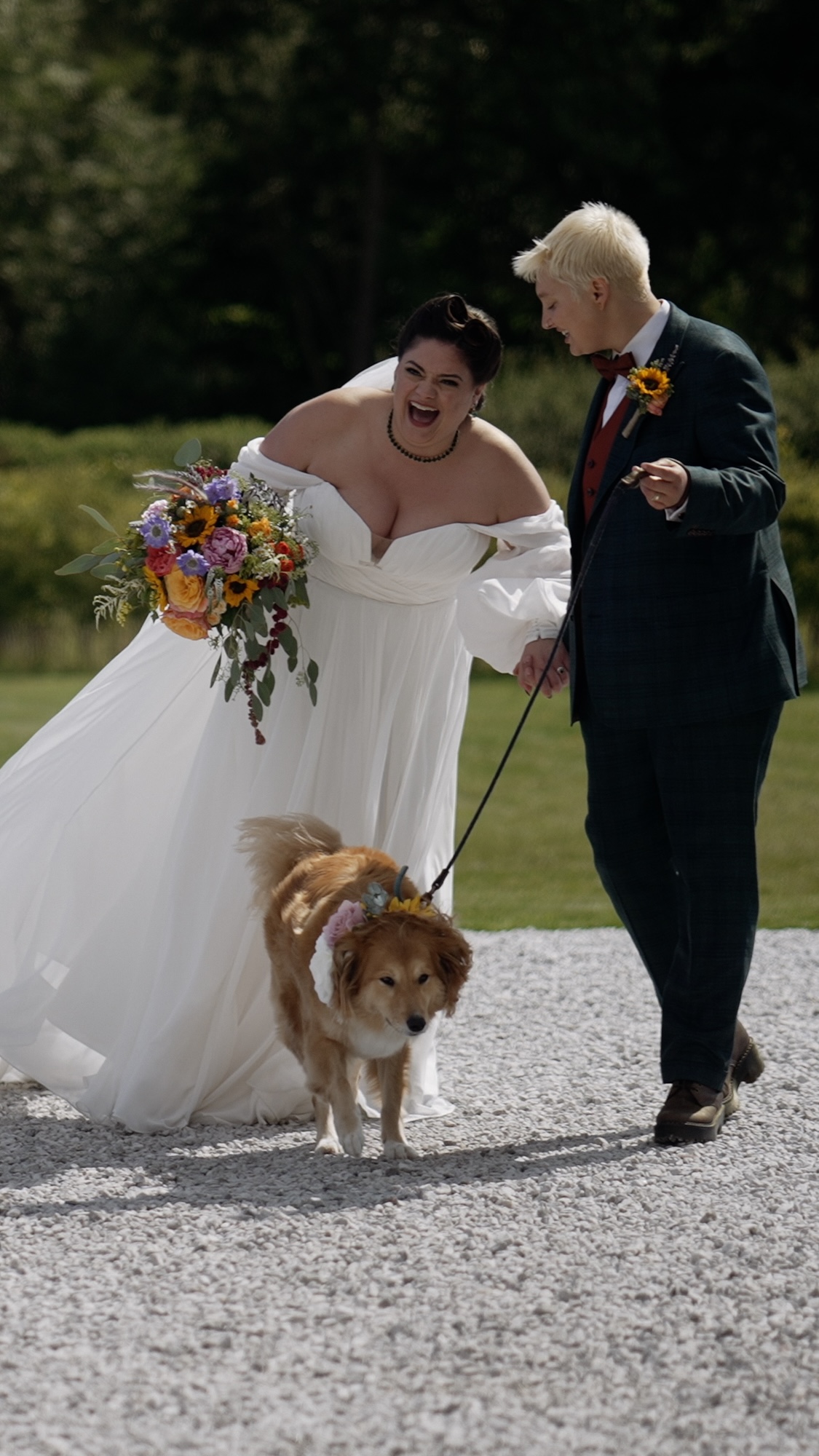 Bride & Bride walking a dog in fron of Hazel Gap Barn