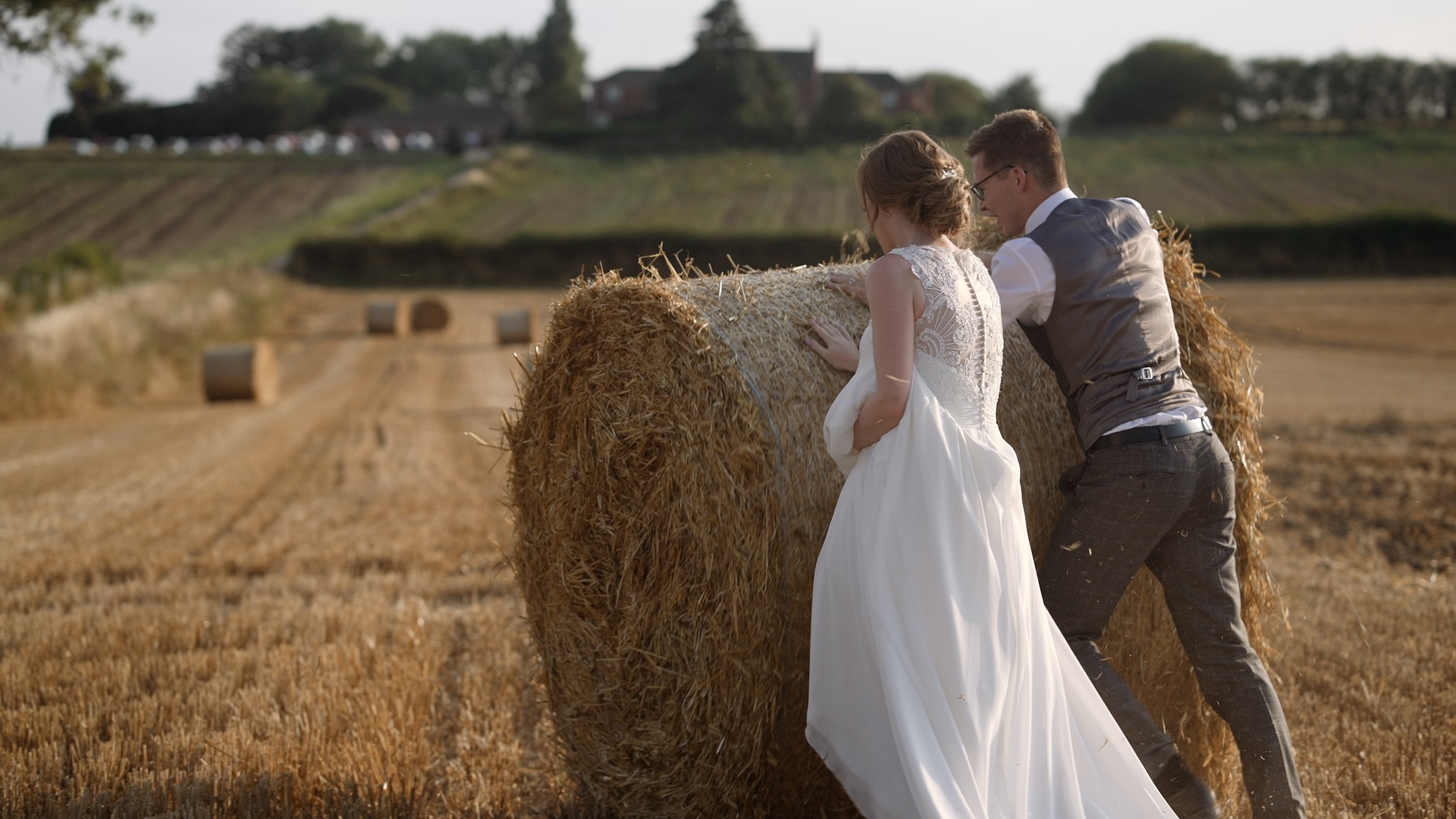 Bride and groom pushing a hay bale at Swancar Farm House
